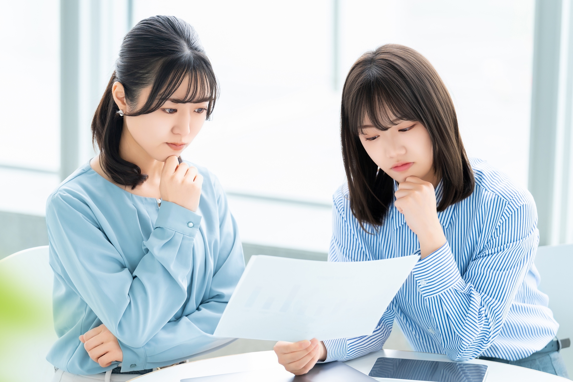 オフィスで書類を見ながら話し合っている二人の若いビジネスウーマン