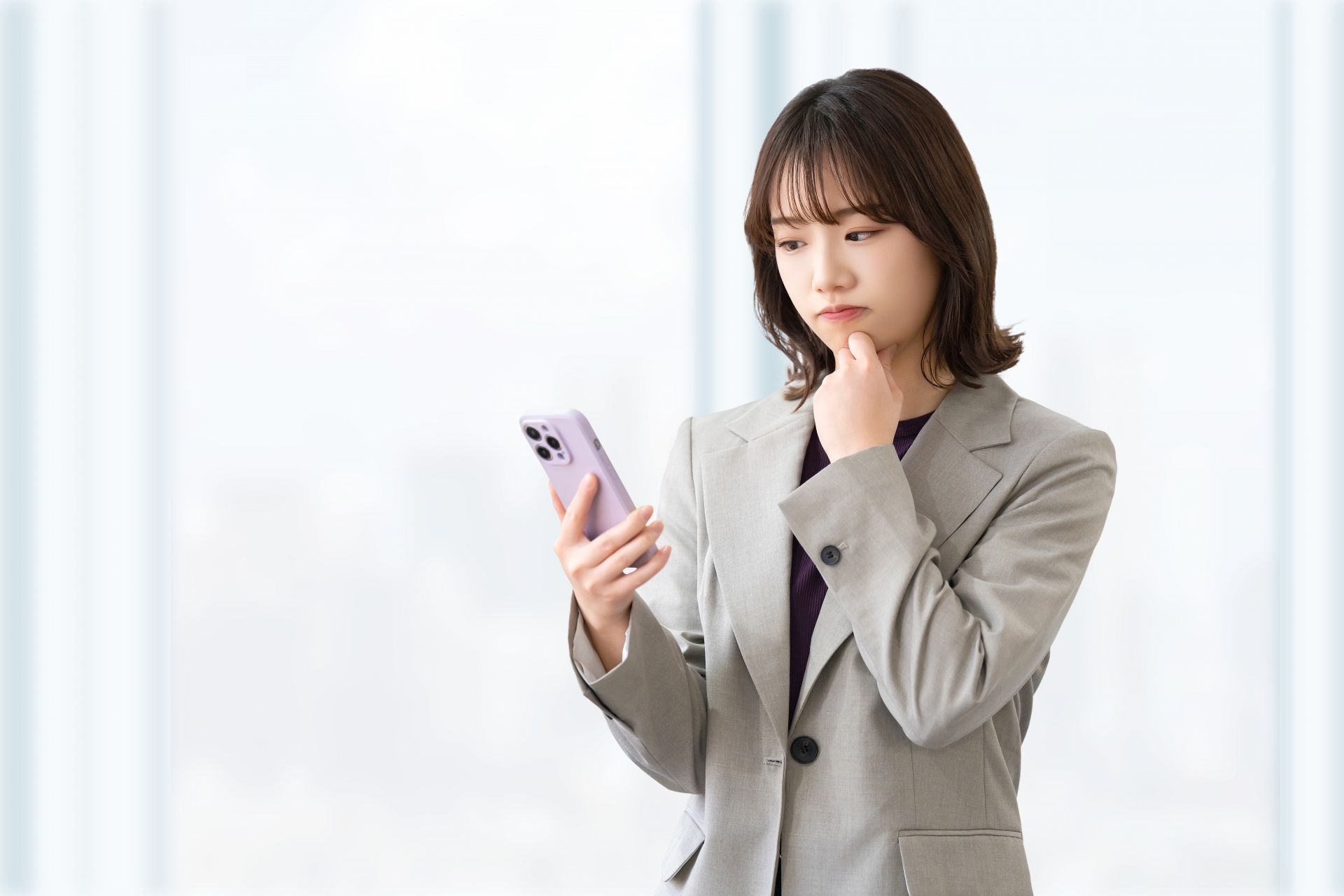 スマートフォンを見て考え込んでいる若いビジネスウーマンのポートレート