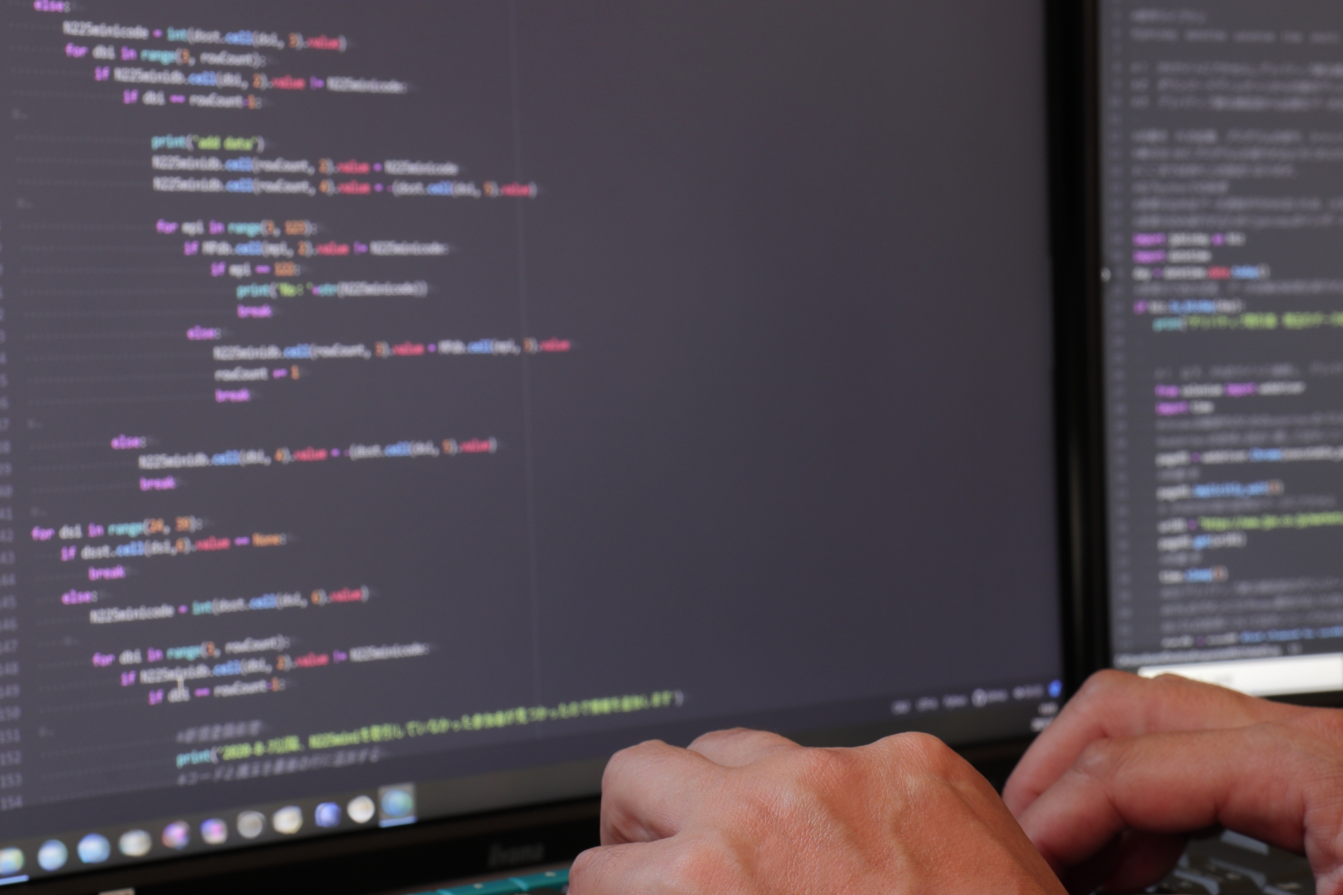 パソコン画面に表示されたコードを打ち込むプログラマー