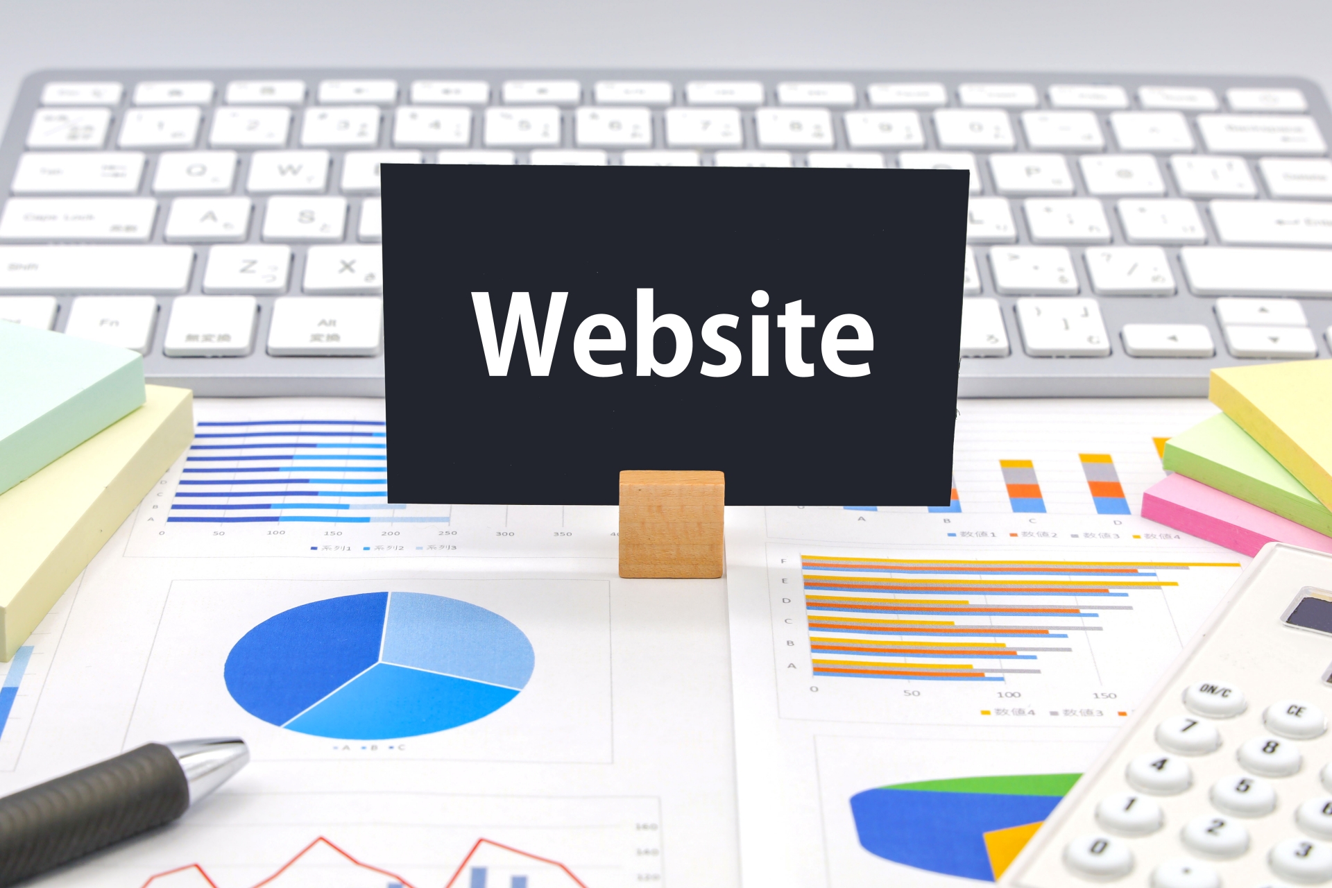 Websiteと書かれたカードとグラフ資料を並べたデスク